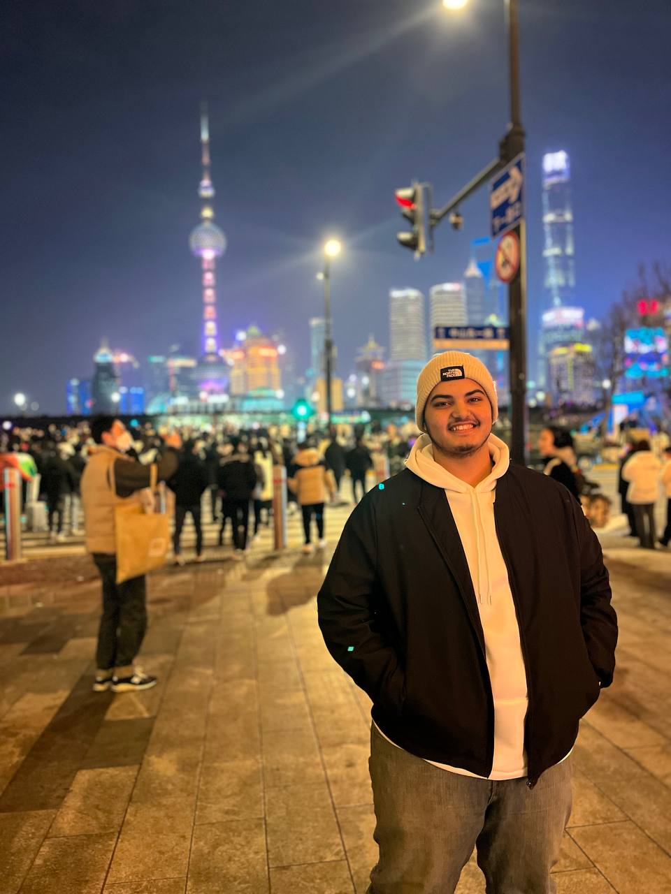 هشام في كورنيش البند بشنغهاي مع أفق المدينة ليلاً — Hesham on the Shanghai Bund waterfront at night
